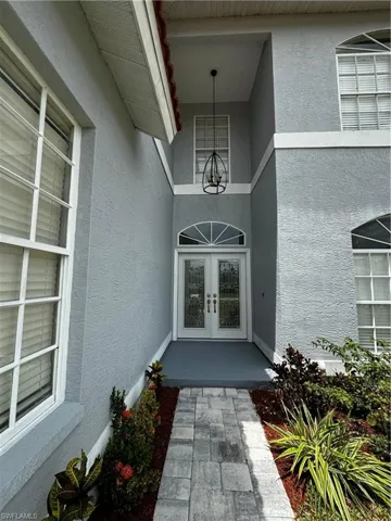 View of exterior entry featuring stucco siding and french doors