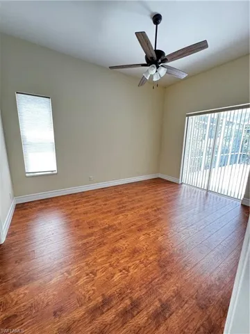 Empty room featuring wood finished floors, a ceiling fan, and baseboards