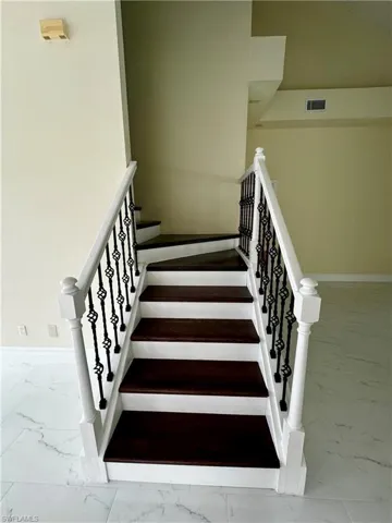 Staircase featuring marble finish flooring and baseboards