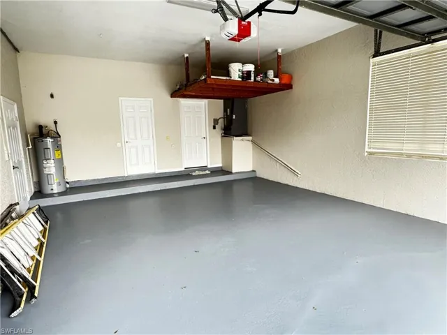 Garage featuring water heater, a garage door opener, and a textured wall