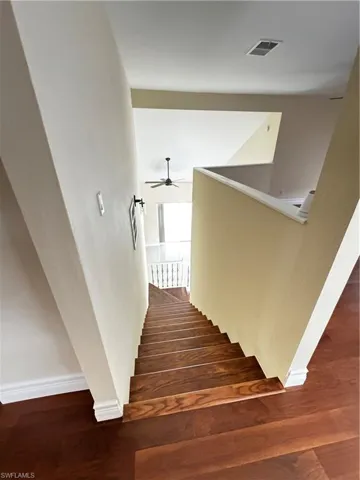 Staircase with ceiling fan, wood finished floors, and baseboards
