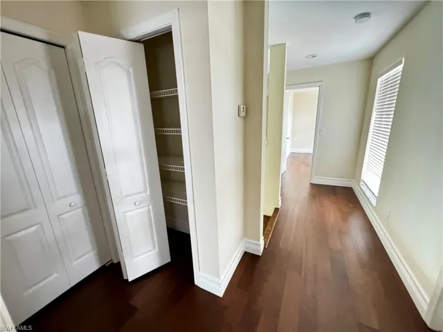 Hallway featuring baseboards and dark wood-style floors