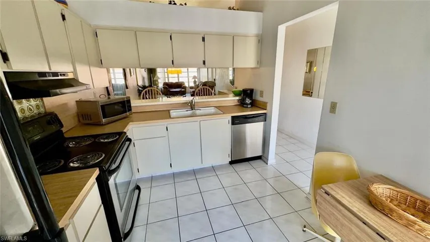 Kitchen featuring light tile patterned floors, appliances with stainless steel finishes, and sink