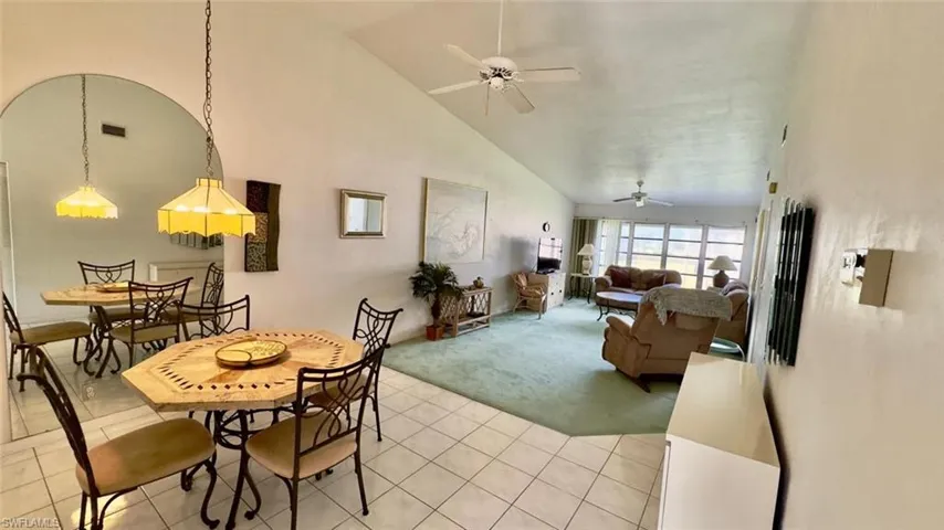 Tiled dining space with ceiling fan and high vaulted ceiling