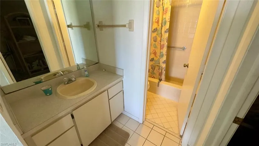 Bathroom with tile patterned floors, vanity, toilet, and a shower with shower curtain