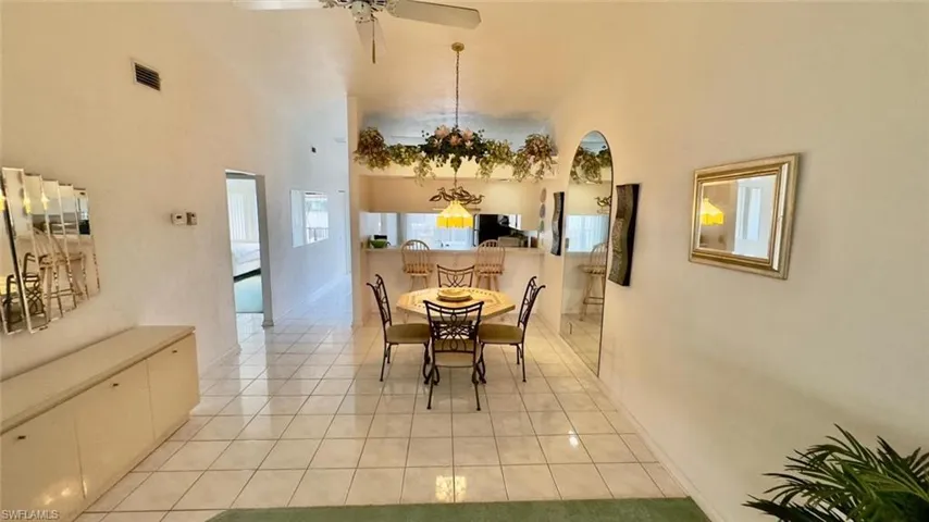 Dining space featuring ceiling fan, light tile patterned flooring, and a high ceiling