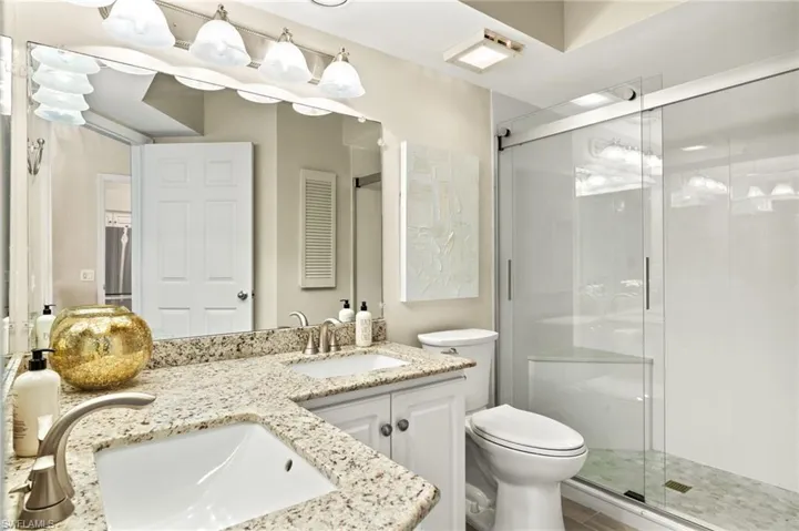Bathroom featuring a shower stall and double vanity