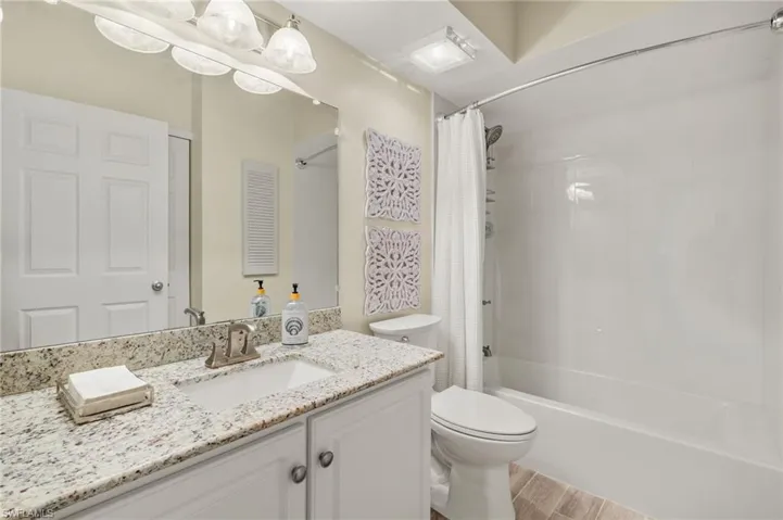Full bath with wood finished floors, vanity, and shower / bath combo with shower curtain