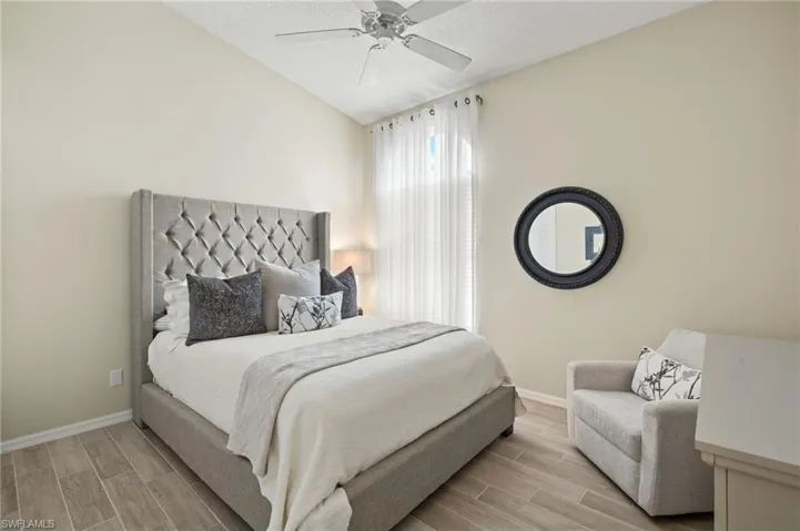 Bedroom with light wood-style floors, lofted ceiling, and a ceiling fan