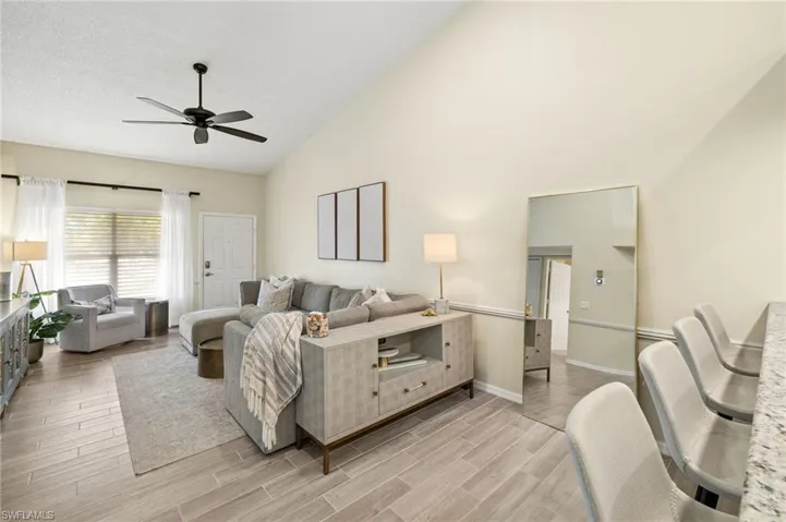 Living area with ceiling fan, high vaulted ceiling, and light wood finished floors