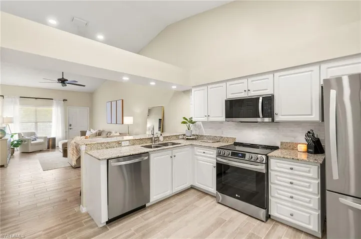 Kitchen featuring appliances with stainless steel finishes, lofted ceiling, a peninsula, open floor plan, and a ceiling fan