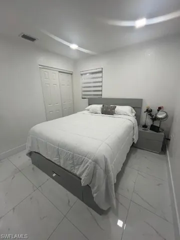 Bedroom with light marble finish flooring and a closet