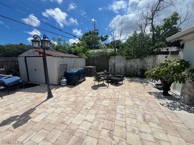 Fenced backyard featuring a shed and a patio area