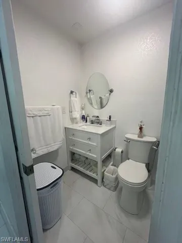 Half bath with vanity, a textured wall, and light marble finish floors
