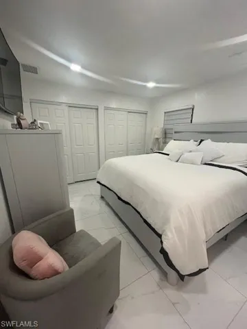 Bedroom with light marble finish floors and two closets