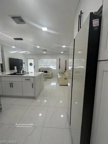 Kitchen with open floor plan, white cabinets, and light stone counters
