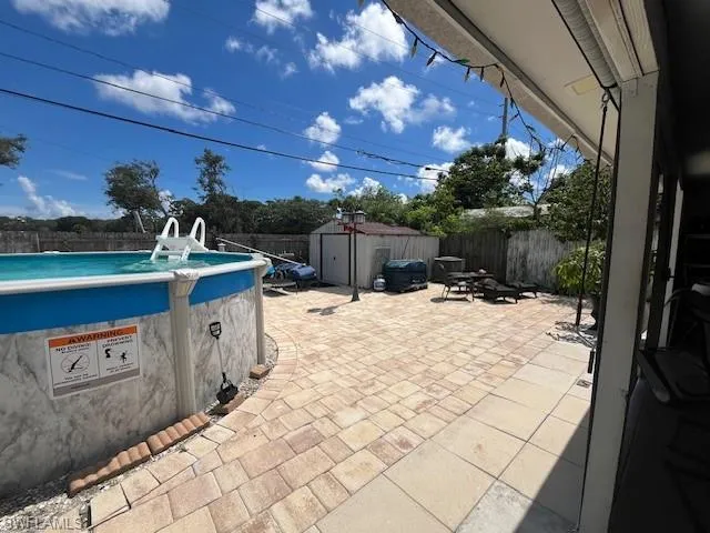 Fenced backyard featuring a patio area and a storage unit