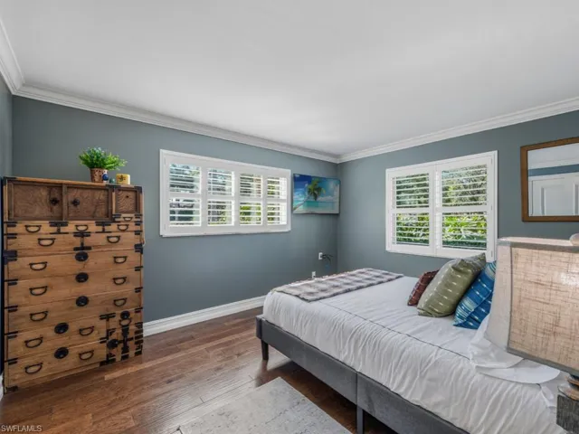 Bedroom with multiple windows, crown molding, and wood-type flooring