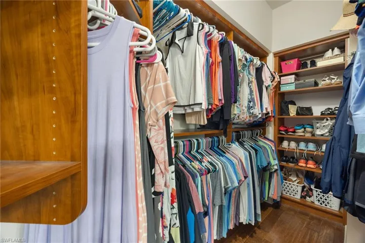 Walk in closet with dark hardwood / wood-style flooring