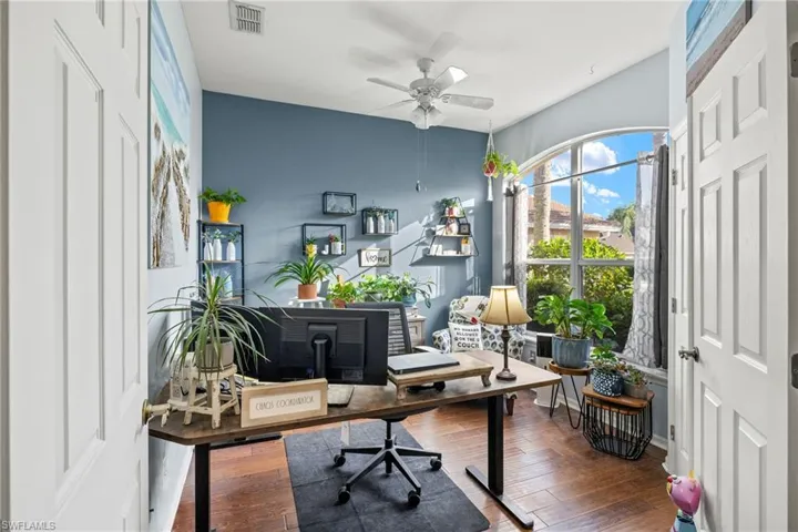Home office with ceiling fan and dark wood-type flooring