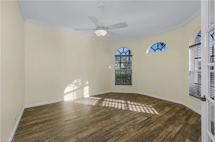 Empty room with ornamental molding, a ceiling fan, and dark wood-style flooring