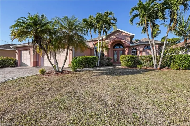 Mediterranean / spanish house with a front yard, stucco siding, driveway, french doors, and a garage