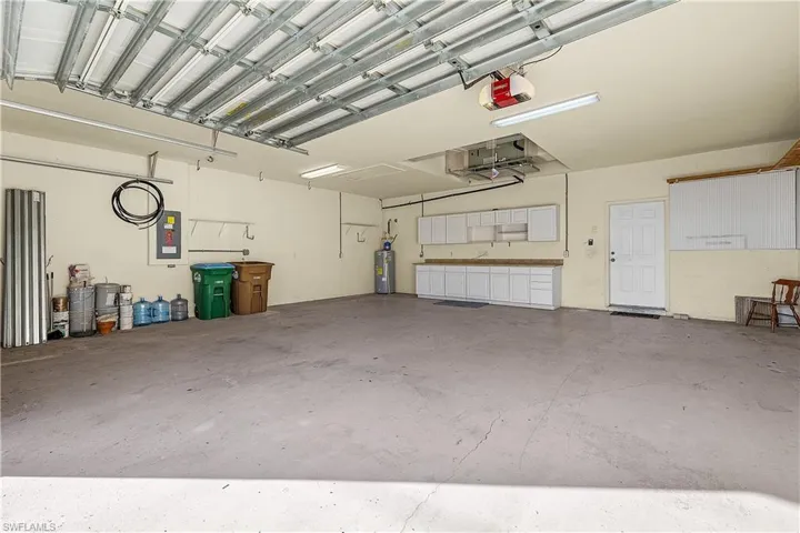 Garage featuring electric panel, a garage door opener, and water heater