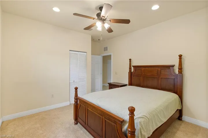 Carpeted bedroom featuring a louvered bifold closet door, recessed lighting, and a ceiling fan with integrated light fixture
