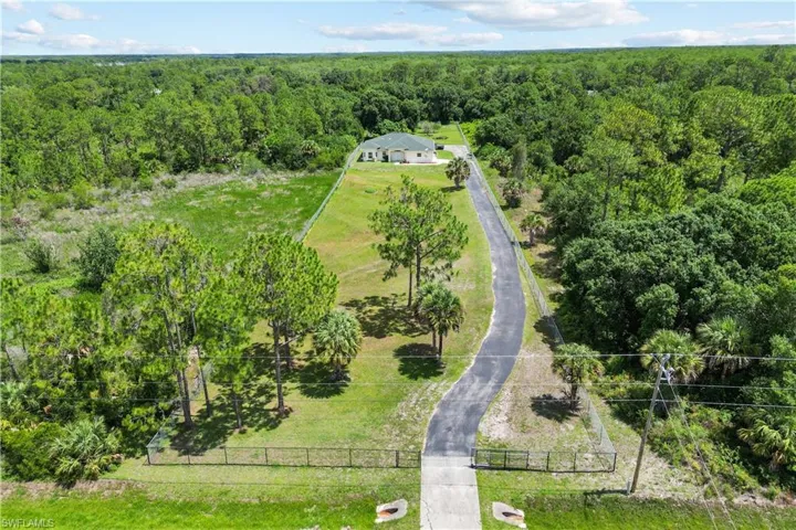 Expansive property featuring a paved driveway leading to a single-story residence