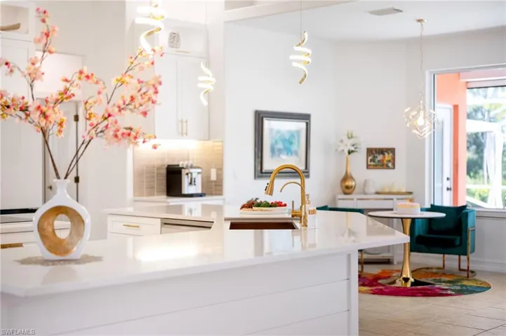Kitchen with white cabinets, backsplash, decorative light fixtures, and light stone counters