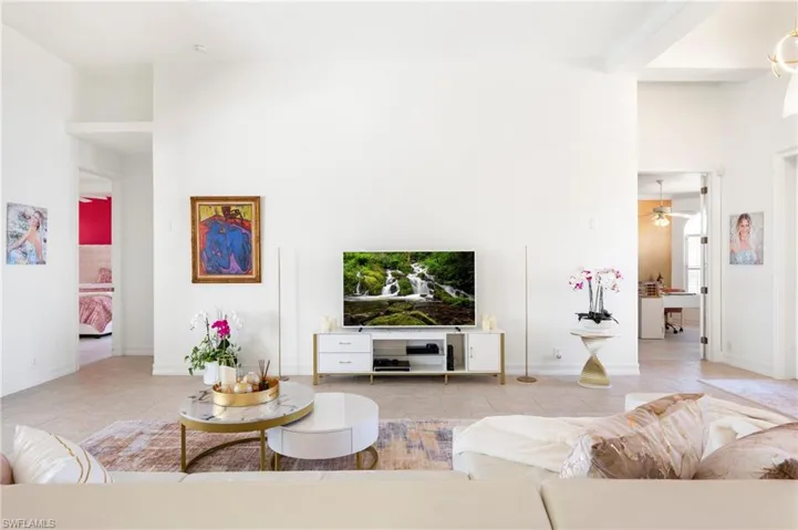 Living room featuring a ceiling fan, light tile patterned floors, and a high ceiling