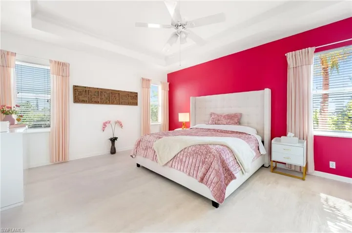 Bedroom featuring a raised ceiling, wood finished floors, and ceiling fan