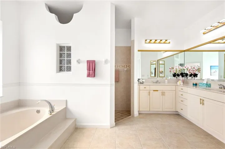 Full bathroom with a walk in shower, double vanity, a bath, and light tile patterned flooring