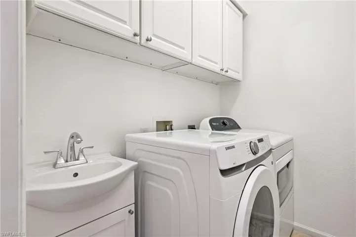 Laundry area featuring cabinet space, washing machine and clothes dryer, and a textured wall