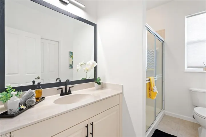 Full bathroom with a stall shower, vanity, and light tile patterned floors