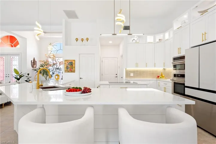 Kitchen with white cabinets, light tile patterned floors, freestanding refrigerator, hanging light fixtures, and decorative backsplash