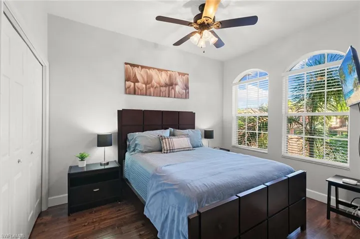 Bedroom featuring baseboards, a ceiling fan, dark wood-style floors, and a closet