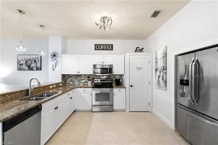 Kitchen featuring decorative backsplash, visible vents, dark stone counters, appliances with stainless steel finishes, and a sink