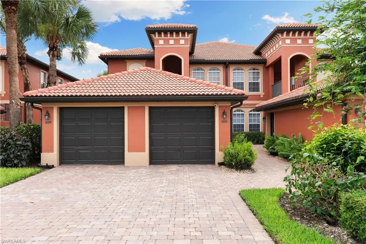 Mediterranean / spanish home featuring a tiled roof, decorative driveway, stucco siding, and an attached garage