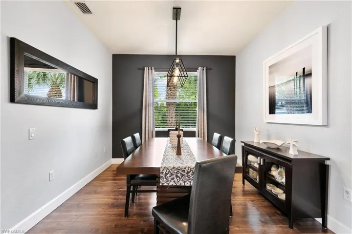 Dining space with dark wood finished floors, baseboards, and visible vents