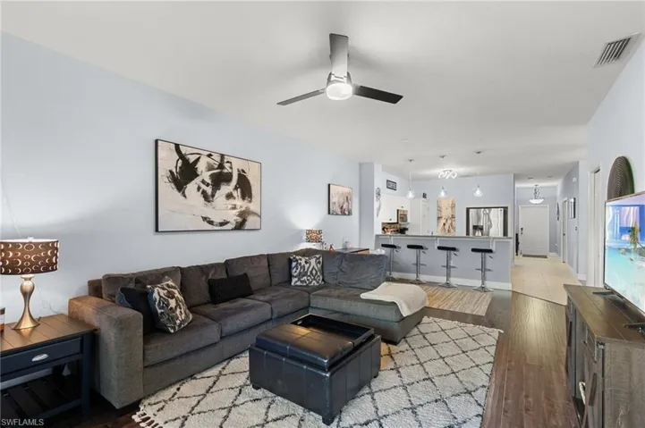 Living area featuring ceiling fan, wood finished floors, and visible vents