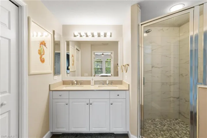 Bathroom with double vanity, a sink, and a stall shower