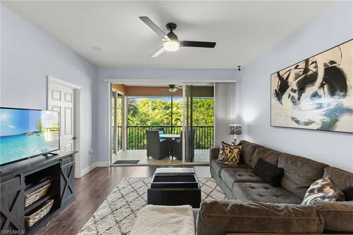Living room featuring dark wood-style flooring, baseboards, ceiling fan, and visible vents