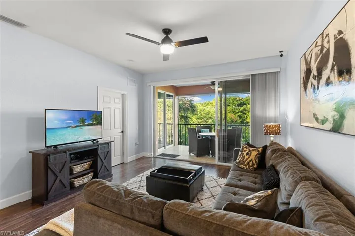 Living area featuring visible vents, a ceiling fan, baseboards, and dark wood-style flooring