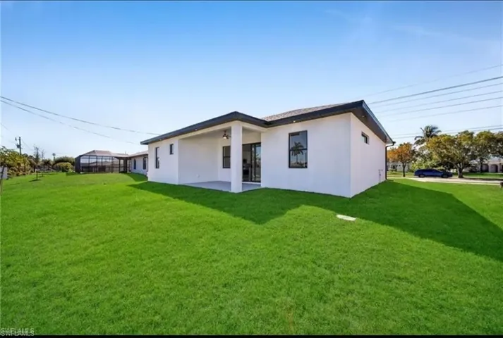 Back of house featuring stucco siding and a yard