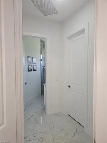 Hallway featuring light marble finish flooring and baseboards