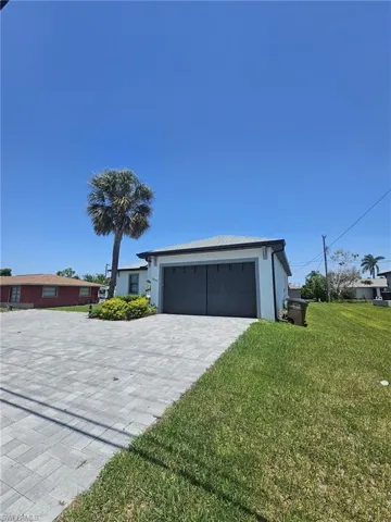 View of front of house featuring a front yard, stucco siding, an attached garage, and decorative driveway
