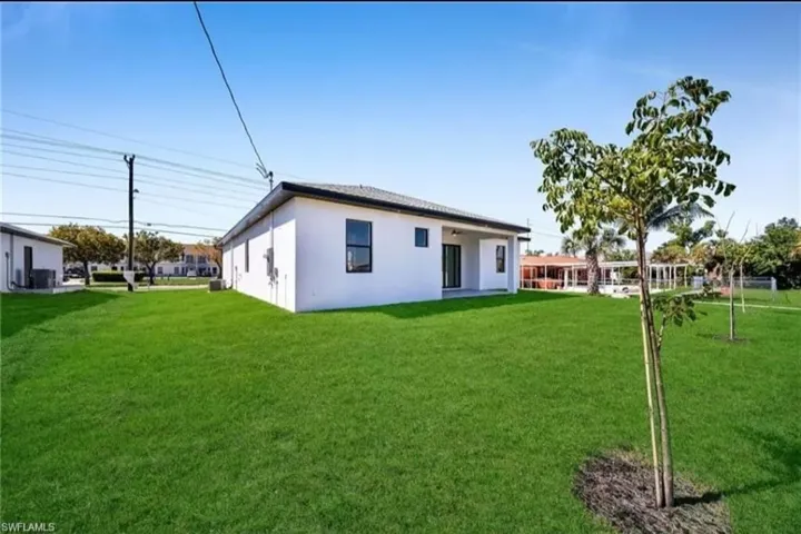 Rear view of property featuring stucco siding and a yard