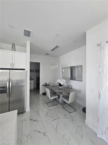 Dining room with baseboards, light marble finish floors, and a textured ceiling
