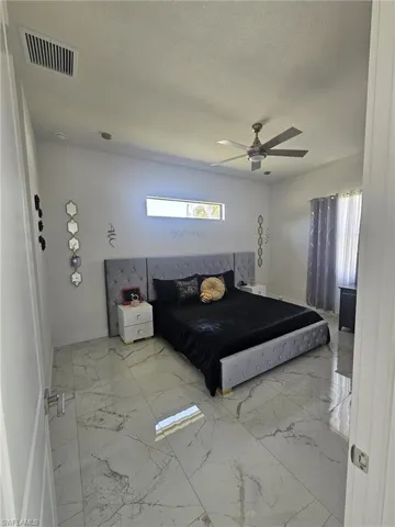 Bedroom featuring baseboards, marble finish flooring, a ceiling fan, and a textured ceiling